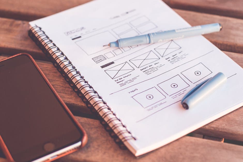 Wireframe sketches and smartphone on a wooden desk